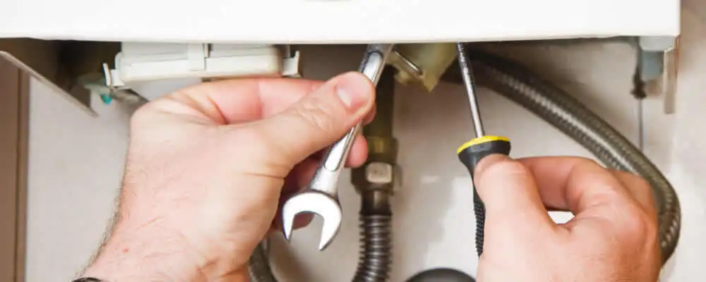 Boiler repair technician tightening pipe fittings and connections in Olathe, KS