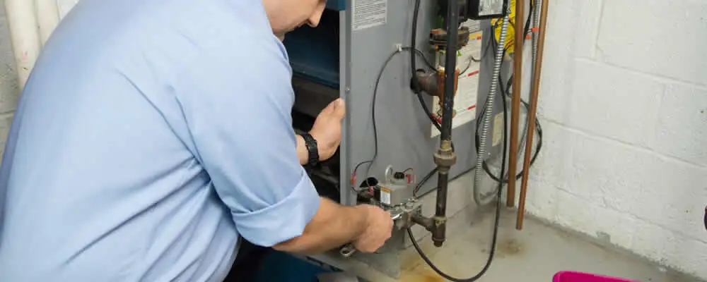 Furnace repair technician inspecting and servicing a home heating system in Olathe, KS
