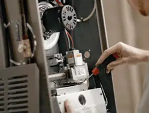 Furnace repair technician inspecting internal components and wiring in Olathe, KS