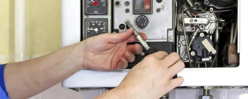 Heating repair technician adjusting boiler controls and components in Olathe, KS
