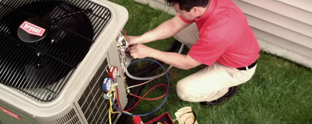 HVAC technician servicing an outdoor air conditioner unit in Olathe, KS