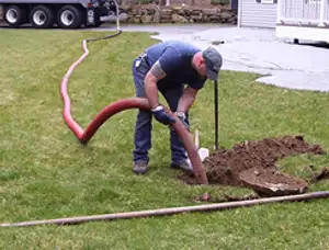 Septic pumping technician servicing a residential septic tank with a vacuum hose in Olathe, KS