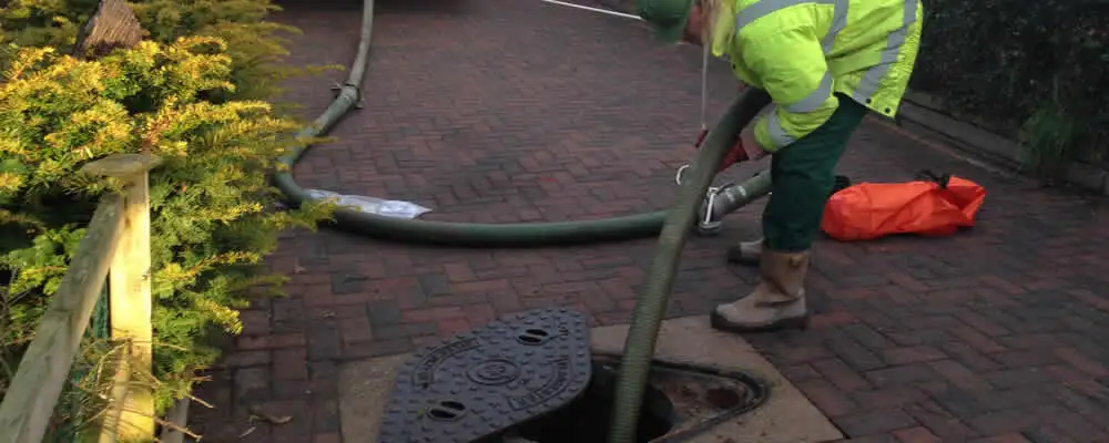 Septic tank cleaning technician servicing a septic tank with a vacuum hose in Olathe, KS