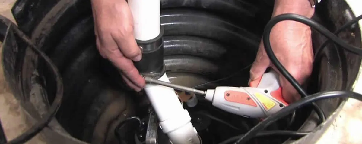 Sump pump installation technician connecting PVC discharge piping in Olathe, KS