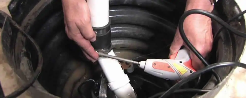 Sump pump installation technician connecting PVC discharge piping in Olathe, KS