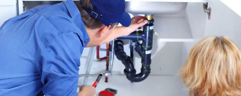 Plumber repairing under-sink drain pipes and fittings in Olathe, KS